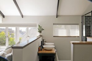 A modern bathroom with a skylight, a large window, and a view of the city.