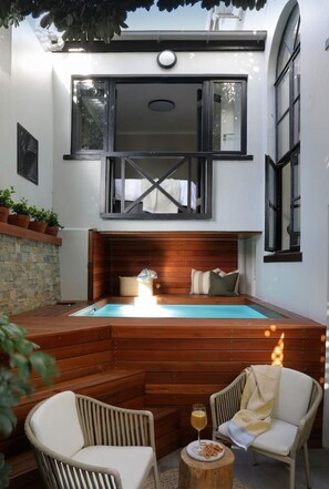 A cozy outdoor seating area with a pool, wooden deck, and chairs.
