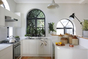 A modern kitchen with white cabinetry, a gas stove, a sink, and a large window with a view of greenery.