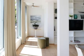 A modern living room with a television, a potted plant, and a bookshelf.