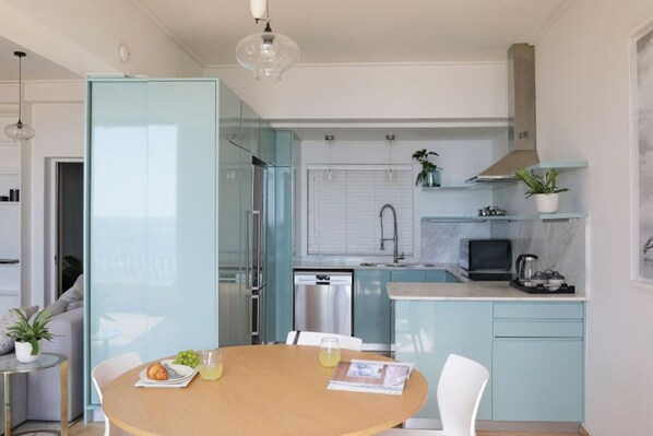 A modern kitchen with a dining area, featuring a round table, chairs, and a small island with a sink.