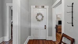 Un couloir avec une porte blanche, un plancher en bois et un porte-manteau fixé au mur.