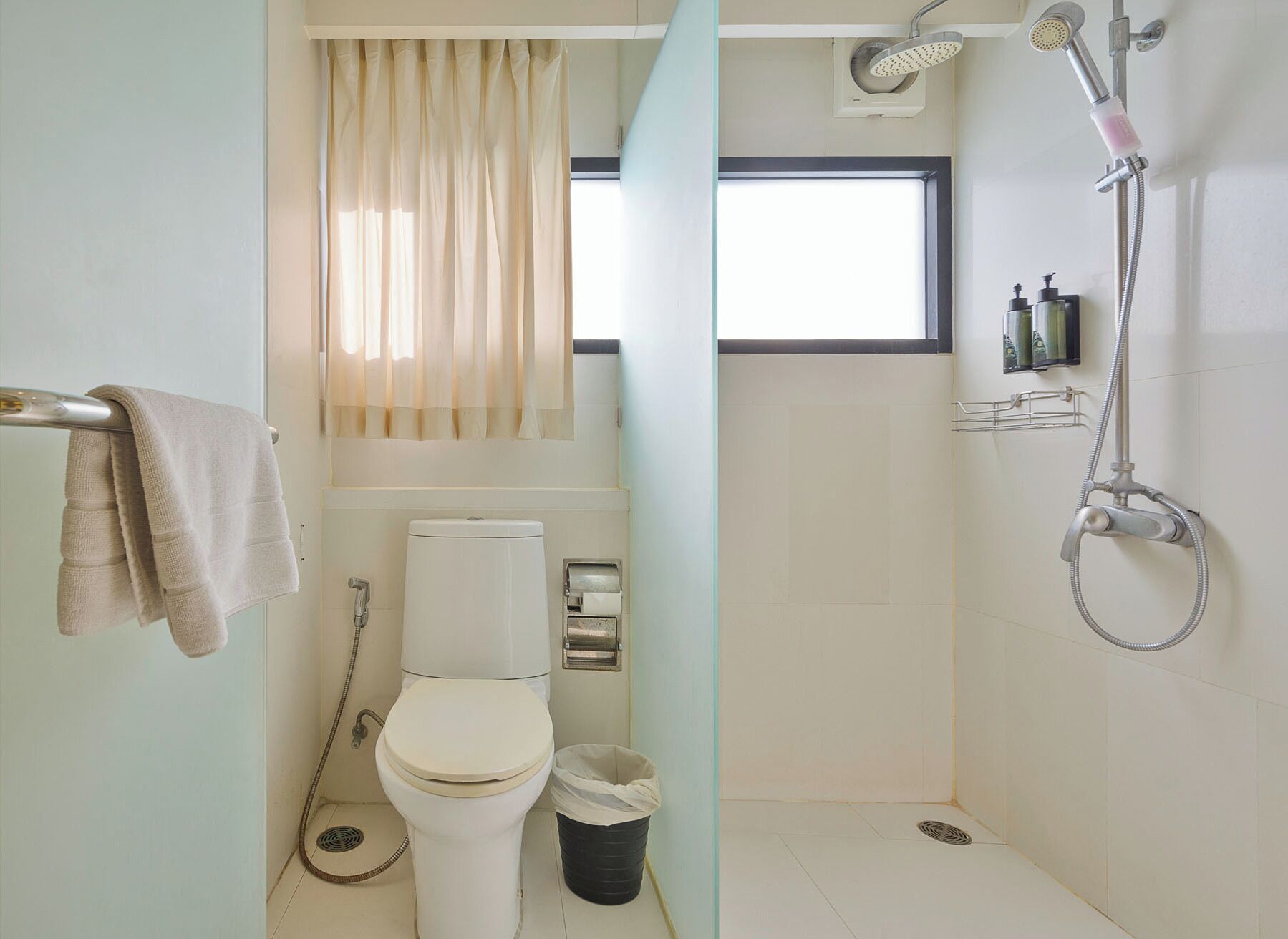 Een kleine badkamer met toilet, douche en raam.