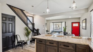 A modern kitchen with a central island, dark cabinetry, and a red accent door. - Stylish 4BR Home • Close to Hospitals + Downtown (Cleveland)