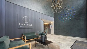 Un hall d’entrée moderne avec un comptoir d’accueil, un espace détente agrémenté de plantes et un mur décoratif orné d’avions en papier.