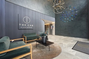 Eine moderne Lobby mit einer Rezeption, einer grünen Lounge und einer Wand mit Papierflugzeugen.