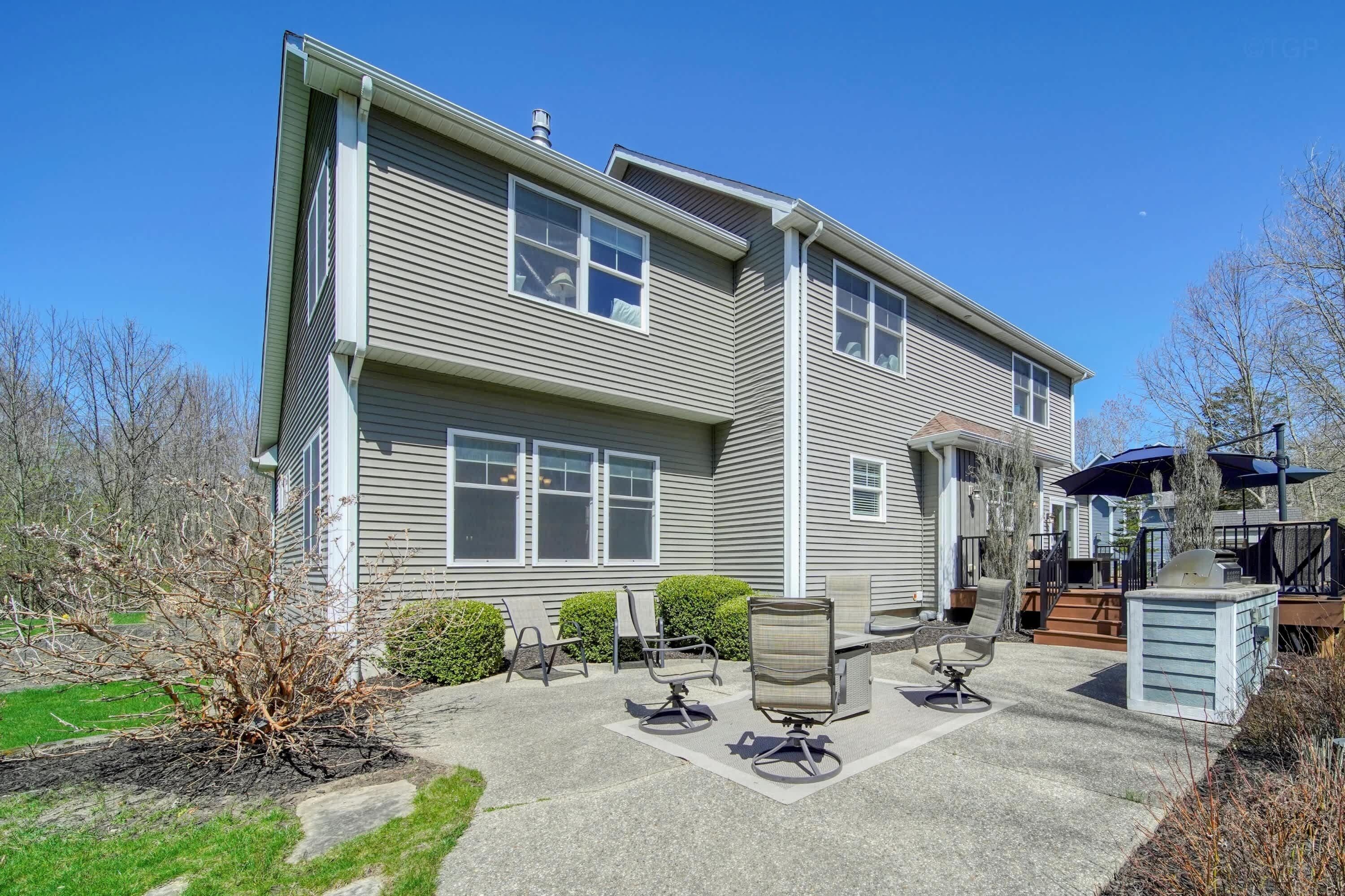 A two-story house with a patio area featuring outdoor furniture and a grill.