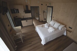 A compact room with a bed, a small desk, and a kitchenette. - CABAÑA O RECUNCHO DO SOR, NORDESTE (O Barqueiro)