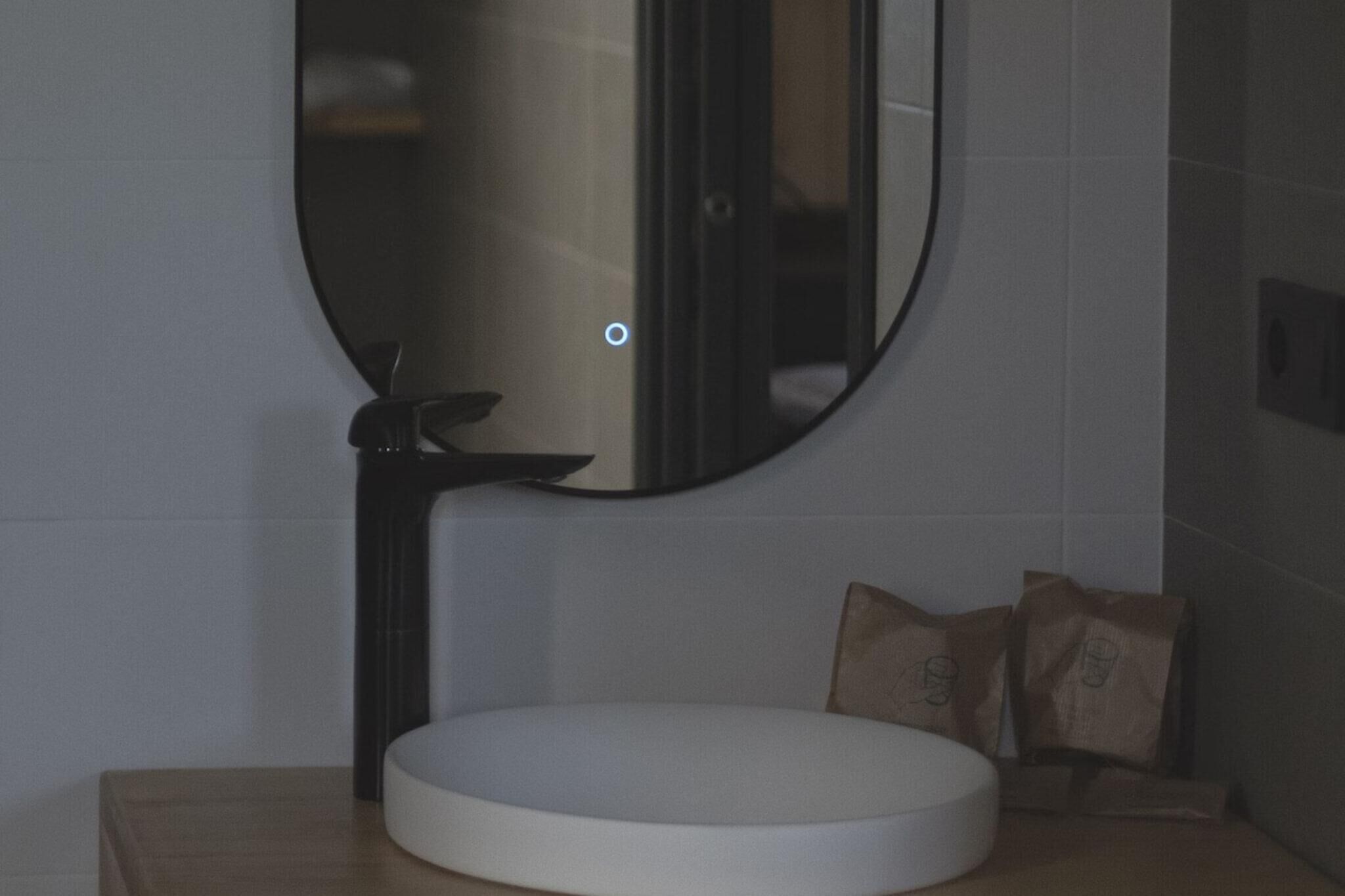 Een badkamer met een rond wastafel, een spiegel en een handdoekhouder.