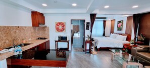 Enjoy a compact retreat with a kitchenette, comfortable seating area, and a cozy bed with white linens.