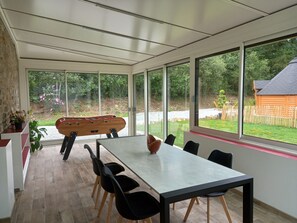 Enjoy meals in this dining area with a view of the lush garden and a wooden cabin.