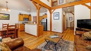 A spacious living area with a wooden floor, a leather sofa, a coffee table, and a television. - Golfers View - on Golf Course - Close to park and lake (McCall)