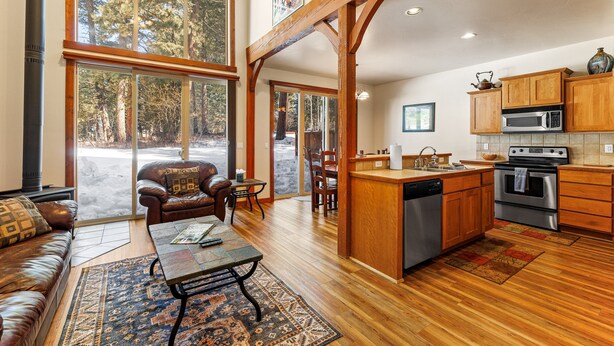 A spacious living room with a fireplace, leather sofa, and a large window overlooking a snowy landscape. - Golfers View - on Golf Course - Close to park and lake (McCall)