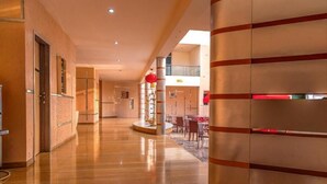 Et hotel lobby med gulv i højglans, en receptionsdisk og en trappe, der fører op til en etage.