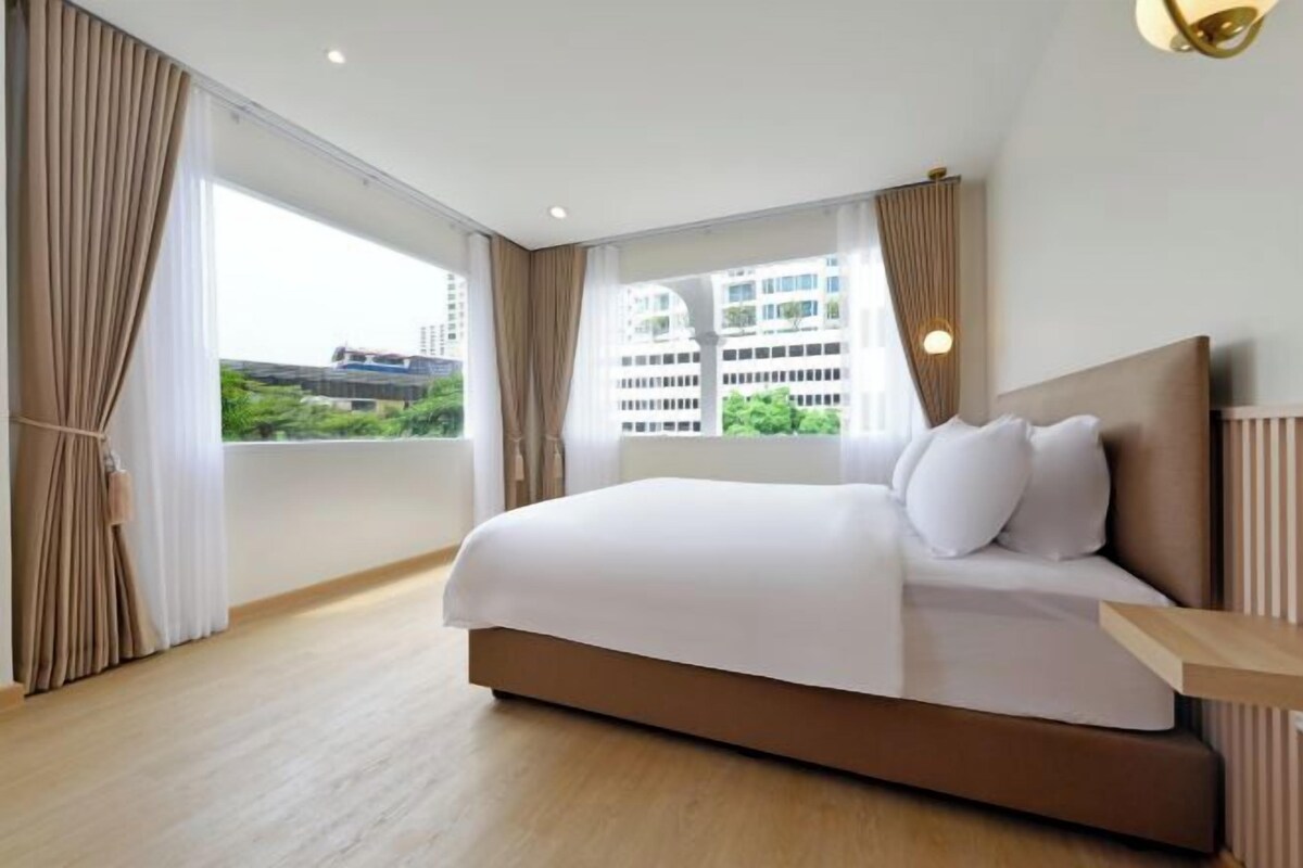 Ett modernt hotellrum med en stor säng, utsikt över staden och en balkong.