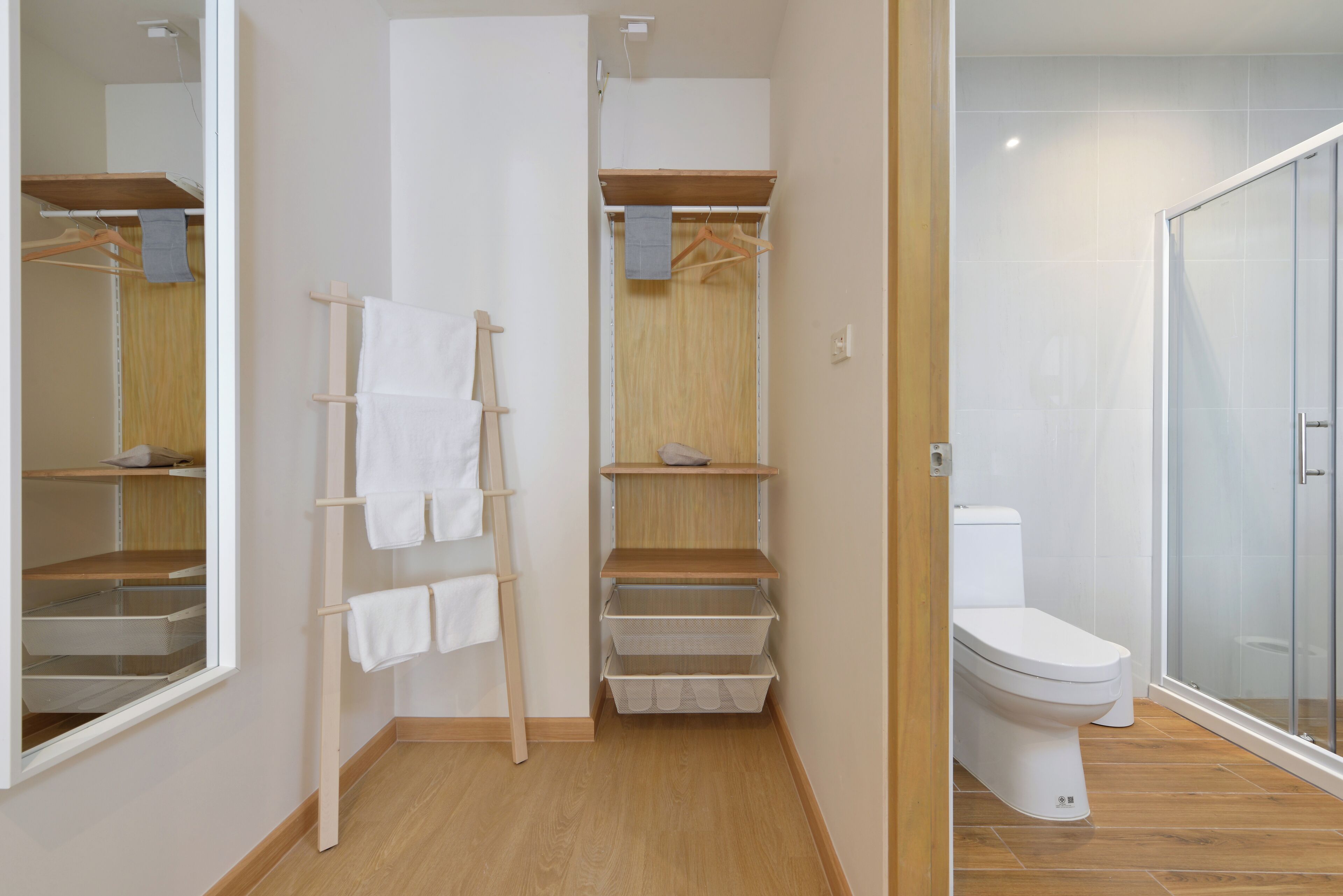 A bathroom with a toilet, a glass shower enclosure, and a wooden floor.