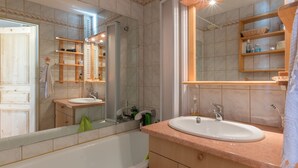 Ein Badezimmer mit einer Badewanne, zwei Waschbecken, einem großen Spiegel und Holzregalen.