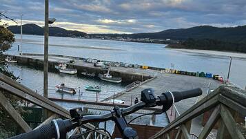 A bicycle parked on a wooden staircase overlooking a harbor with boats and a cloudy sky.