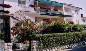 Enjoy the view from the upper-floor balcony with potted plants and a stone wall in front.