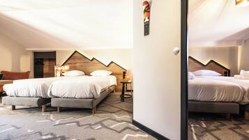A hotel room with two beds, a wooden headboard, a small table with a lamp, and a patterned carpet.