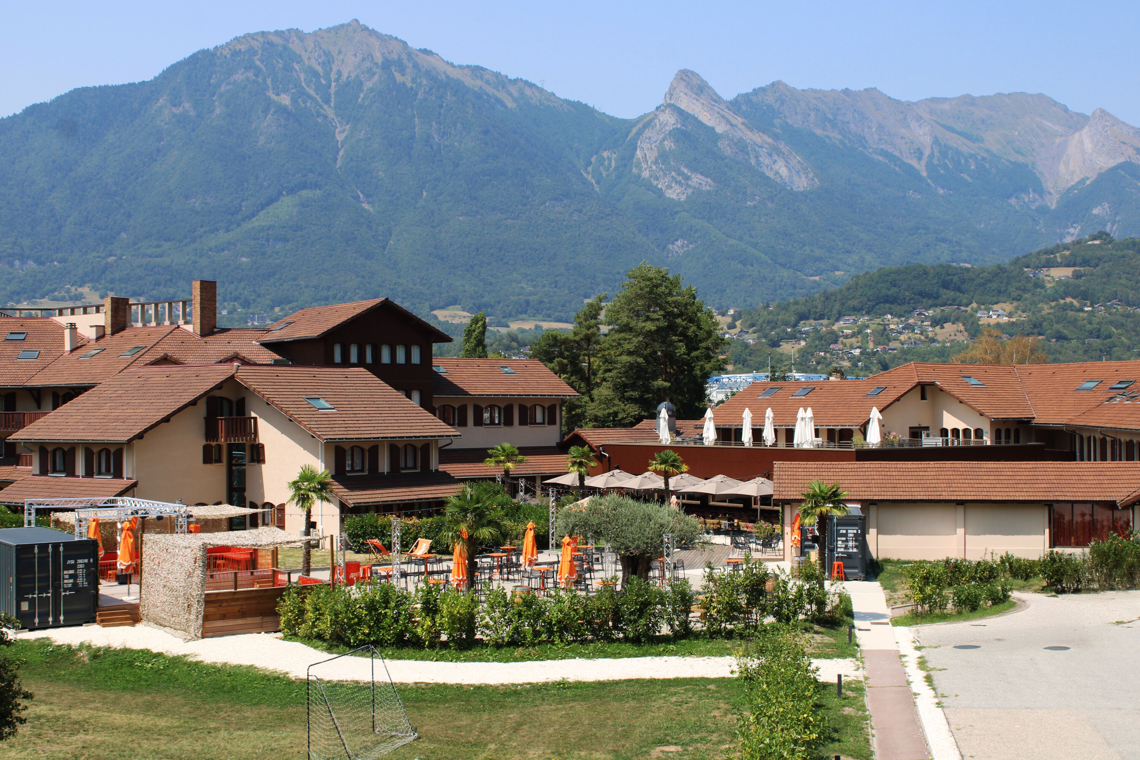 Ein Hotel mit mehreren Gebäuden, Außenbereichen zum Sitzen und einer Bergkulisse.