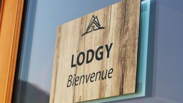 A wooden sign with the words 'LODGY' and 'Bienvenue' indicating a welcome sign, likely at a lodging establishment.