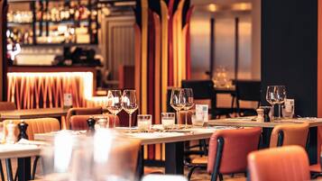 Een restaurant met gedekte tafels, glazen en een bar op de achtergrond.