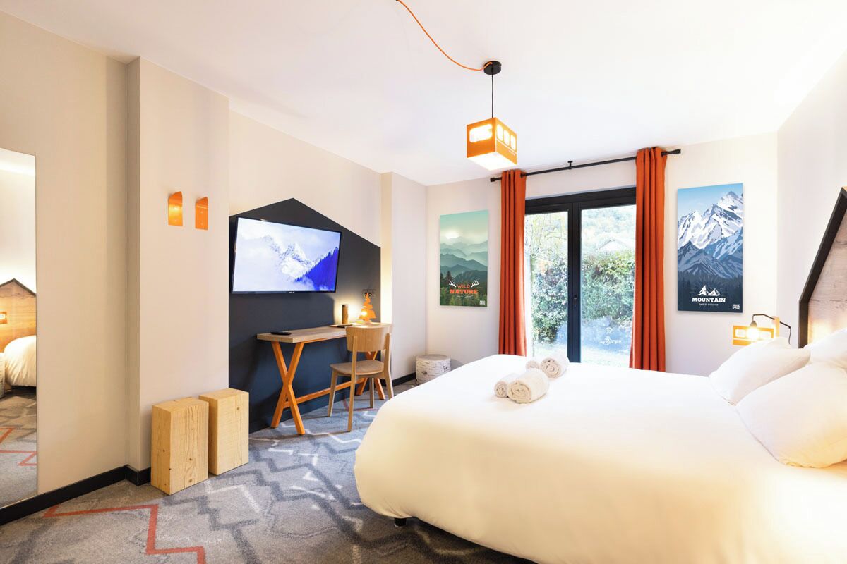 Una habitación de hotel con una cama grande, un escritorio con una silla, un televisor y una ventana con cortinas.