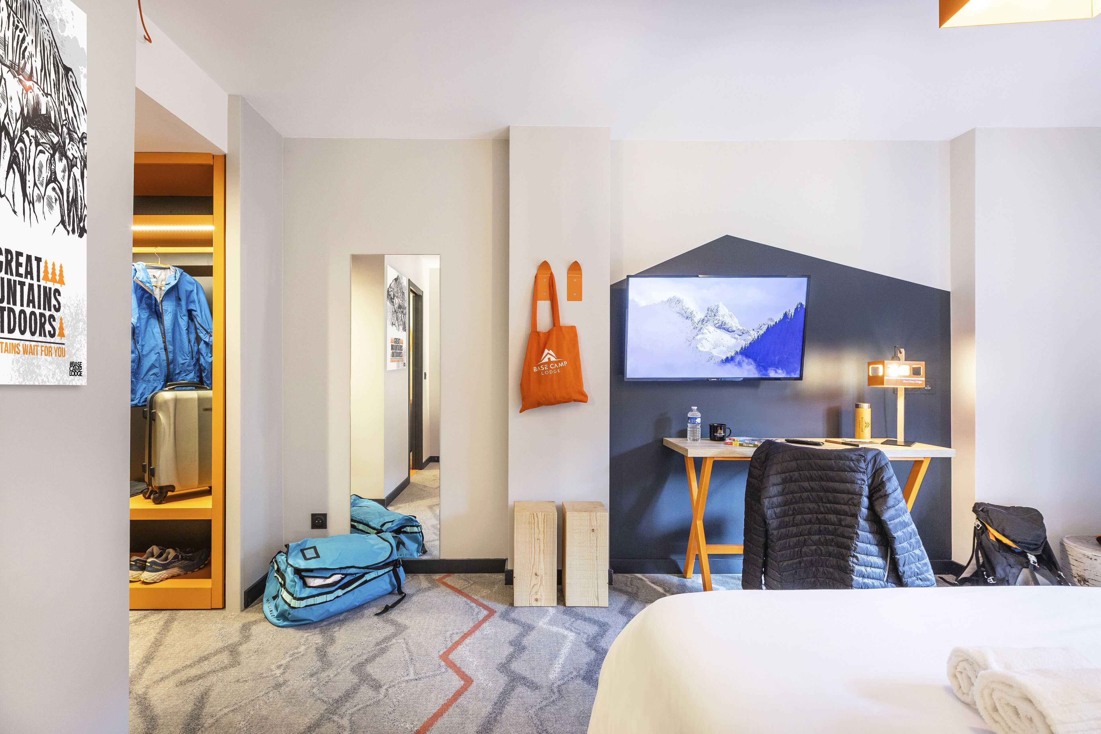 Habitación de hotel con cama, escritorio con computadora, televisor, armario y baño.