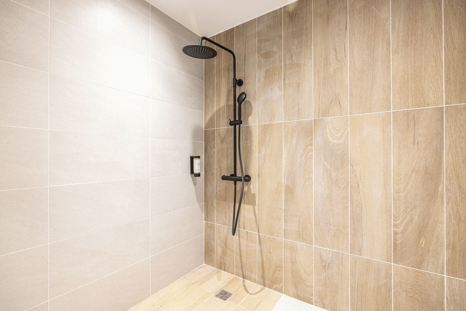 A modern shower area with a rain showerhead, a handheld showerhead, and a handheld massager.