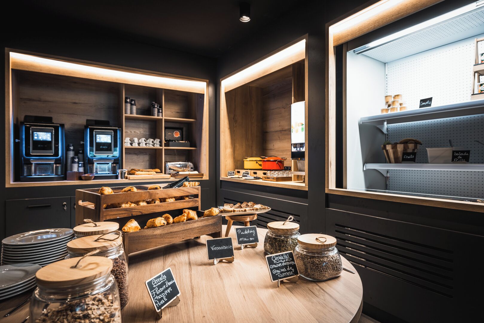 A café interior with wooden shelves displaying pastries and a coffee machine.