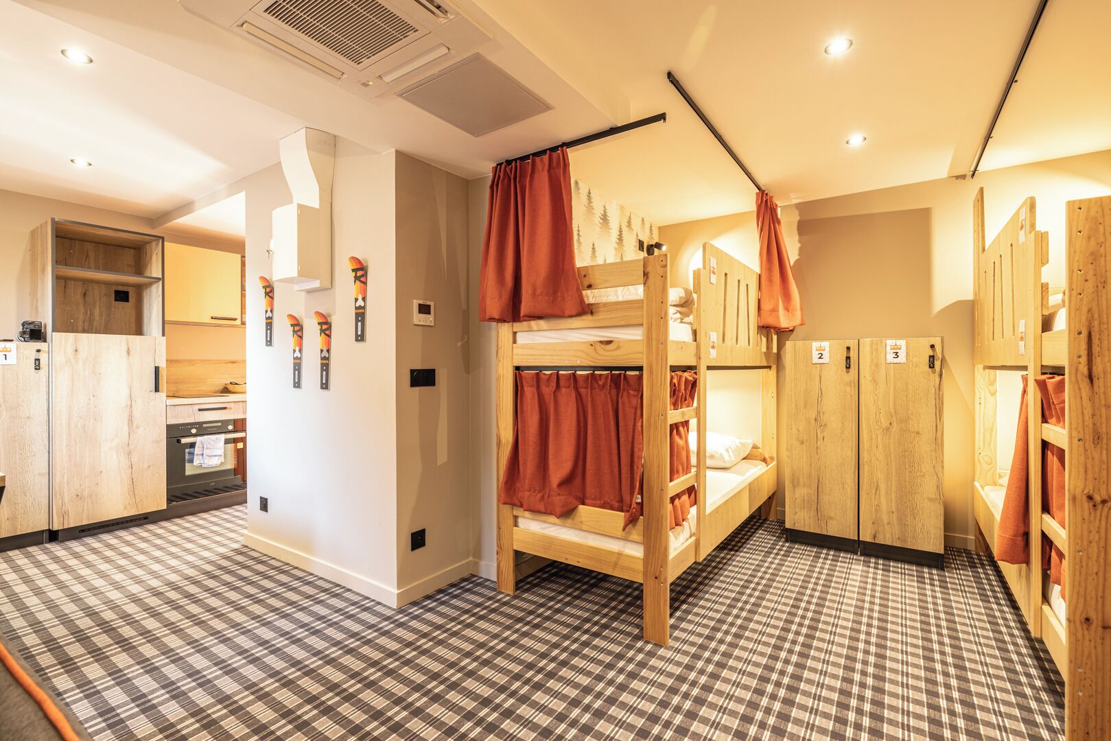 A room with bunk beds, a kitchen area, and a checkered floor.