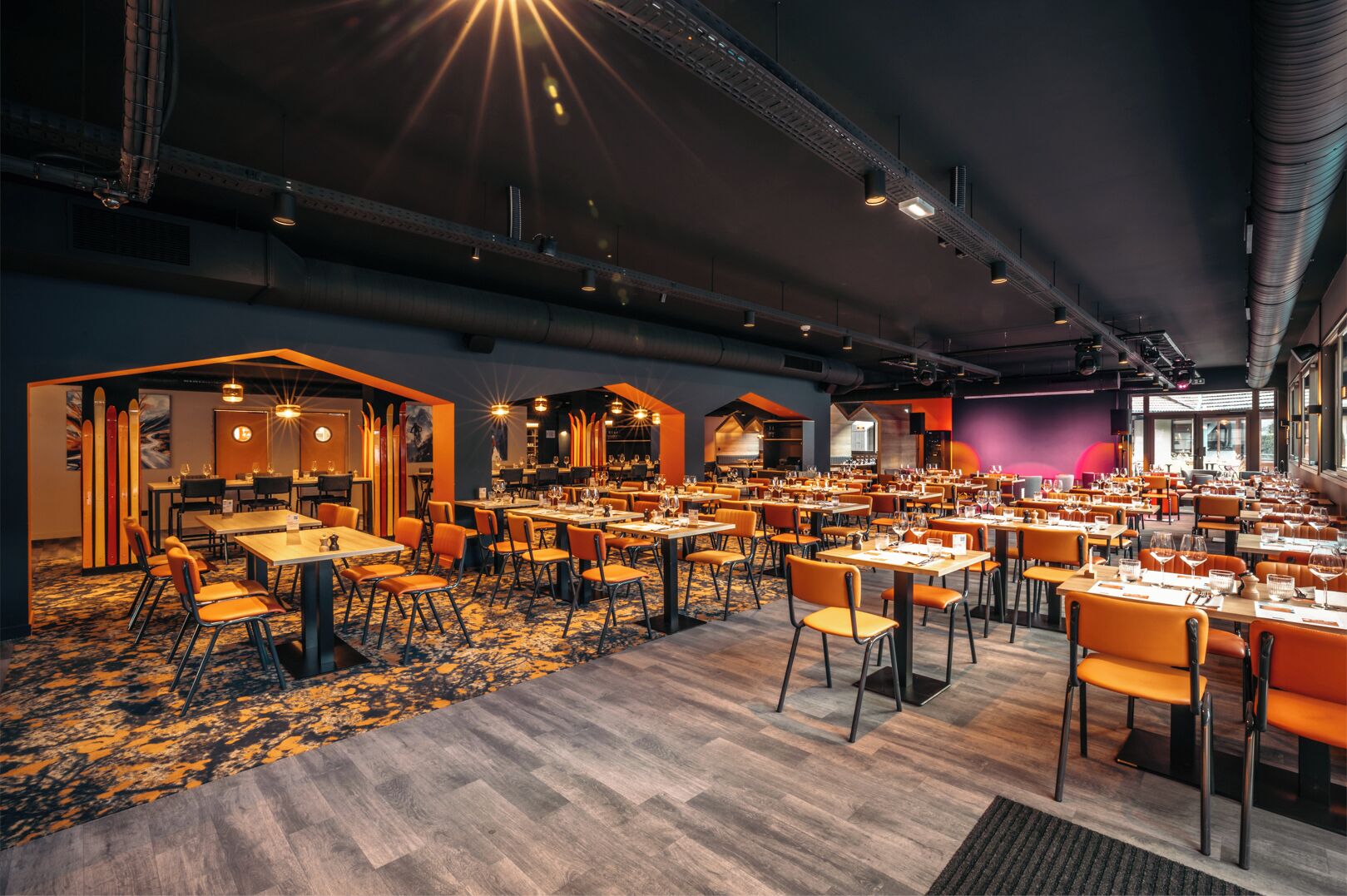 Un restaurant spacieux doté de plusieurs espaces de restauration, de hauts plafonds et d’un éclairage moderne.