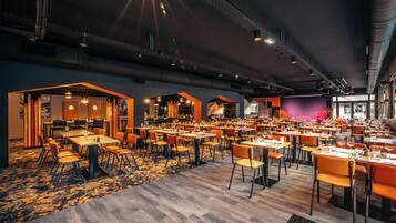 Un restaurant spacieux doté de plusieurs espaces de restauration, de hauts plafonds et d’un éclairage moderne.