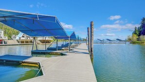 A dock with boats, a covered area with blue canopies, and a clear view of the water and distant mountains.