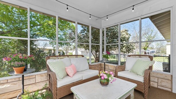 A sunroom with wicker furniture, large windows, and potted plants. - Vintage Veranda - Ping Pong Table & More! (Fredericksburg)