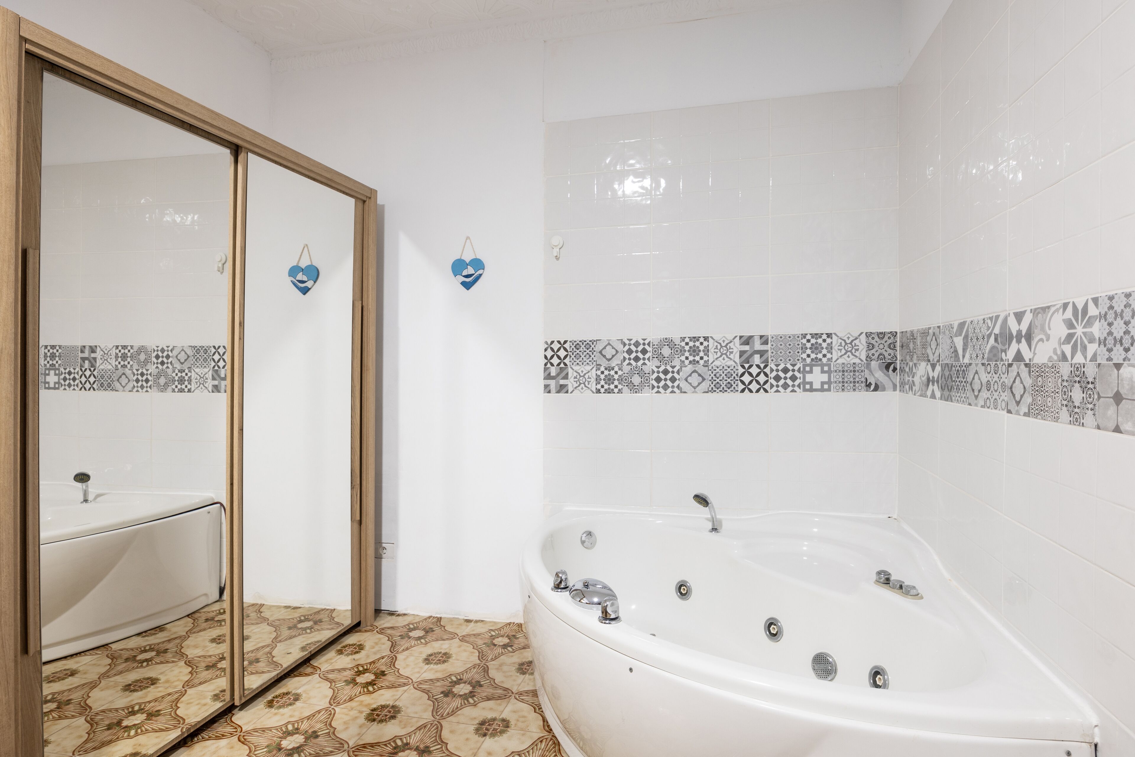 Un baño con bañera, lavamanos y azulejos estampados en las paredes.