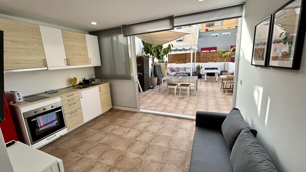 A compact kitchen with modern appliances and a dining area with a sofa and table. - KITE & SURF NOMAD HOUSE (Las Palmas de Gran Canaria)