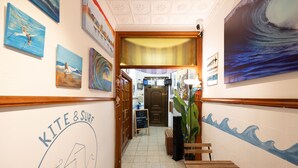 A hallway with artwork, a sign for 'KITE & SURF', and a wooden bench. - KITE & SURF NOMAD HOUSE (Las Palmas de Gran Canaria)