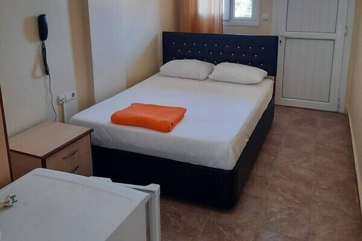 A bedroom with a bed, a desk, and a wardrobe.