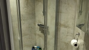A modern bathroom with a glass-enclosed shower, a white sink, and toiletries on the counter. - Suite Overlooking Hyde Park (London)