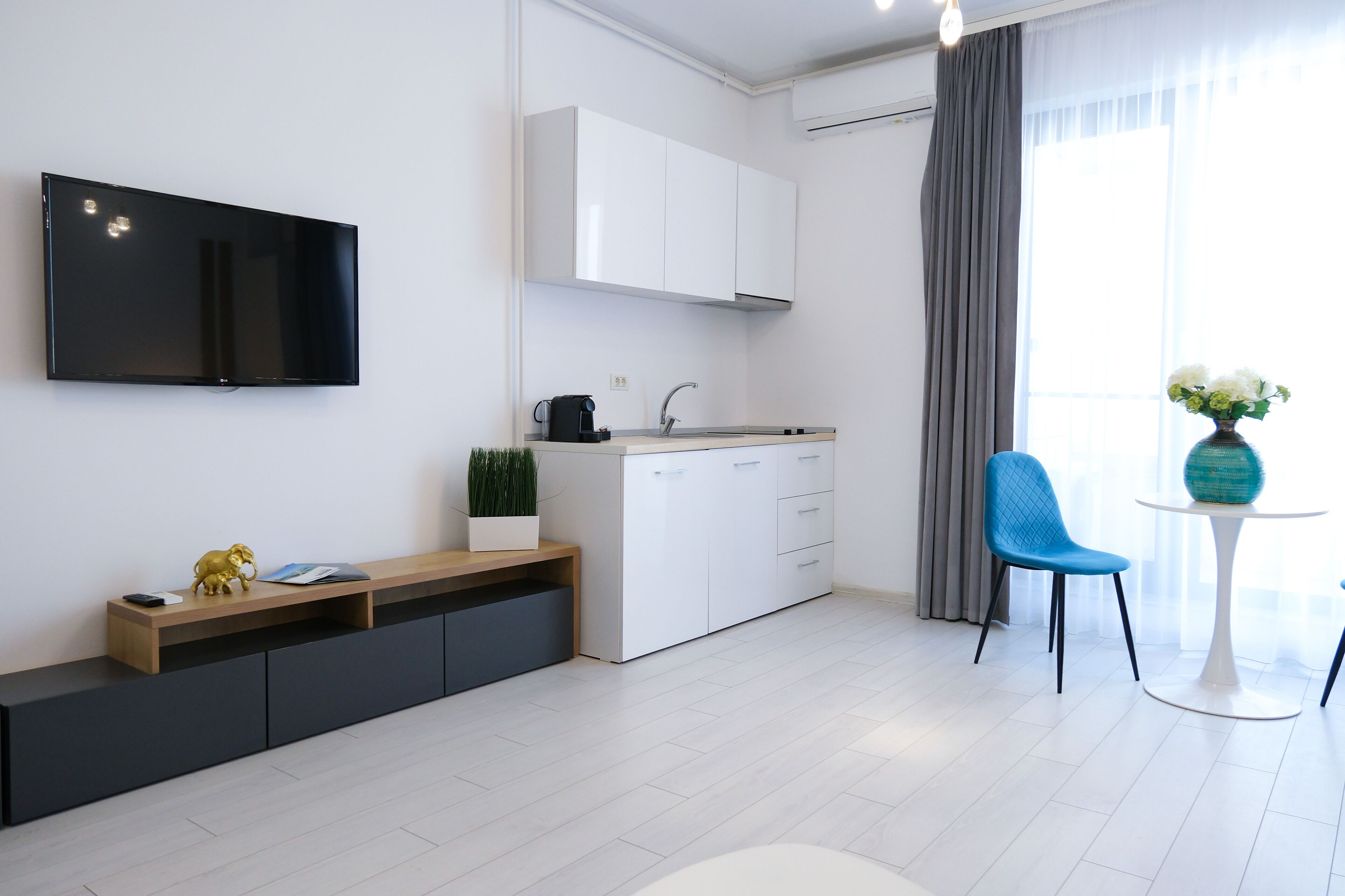 A modern kitchen with white cabinets, a built-in TV, and a coffee machine.