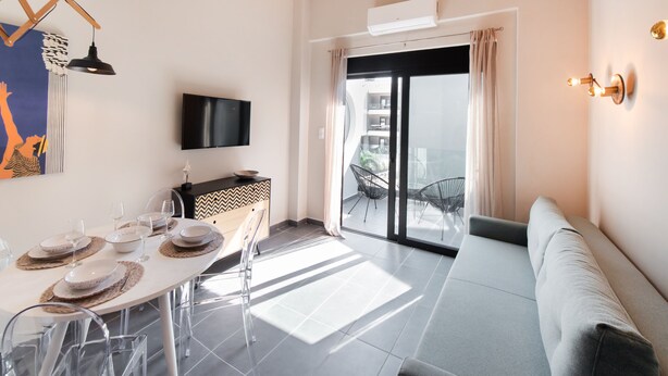 A modern living room with a dining area, a flat-screen TV, and a balcony with a view. - Gateway in Lefkada (Lefkada)