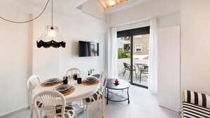 A modern dining area with a round table, white chairs, a black and white striped sofa, and a small side table. - Gateway in Lefkada (Lefkada)