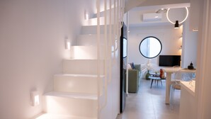 A modern interior with a staircase, a dining area, and a round mirror. - Gateway in Lefkada (Lefkada)