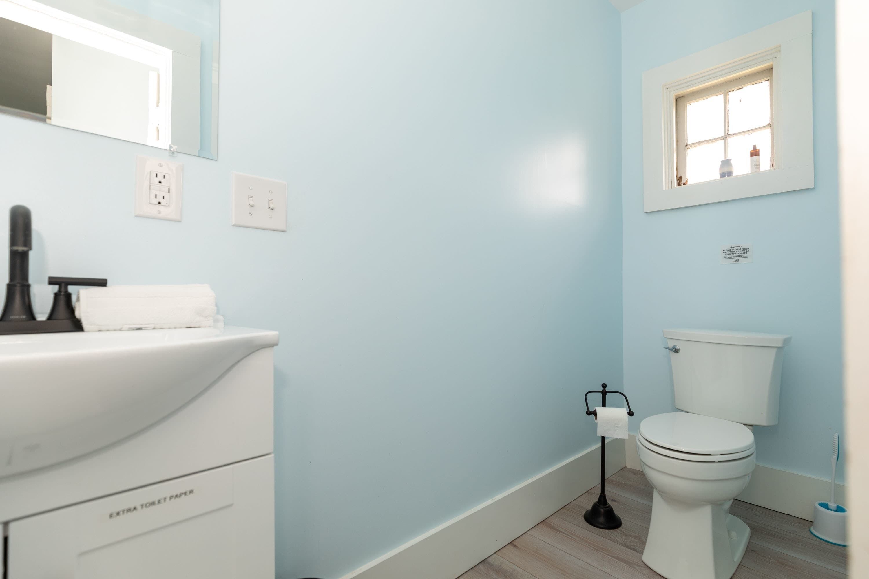 A bathroom with a white sink, a toilet, and a window.
