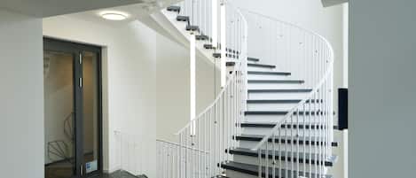 Una escalera moderna con barandillas blancas y peldaños negros que conduce a un piso superior.