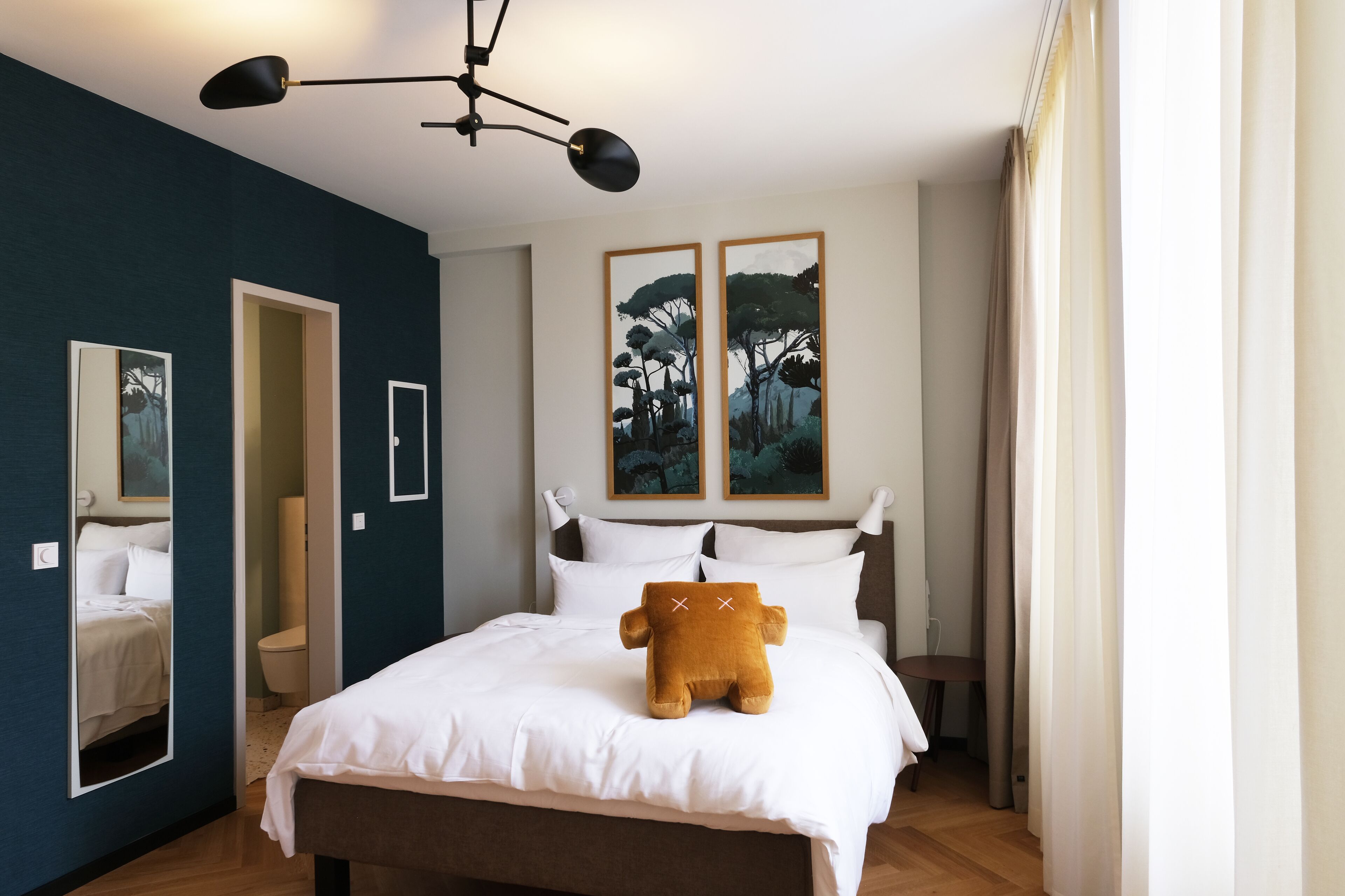 A bedroom with a bed, a nightstand, a lamp, and two framed pictures on the wall.
