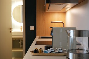 Una cocina moderna con cafetera, hervidor y una bandeja con cápsulas de café.