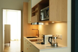 A modern kitchen with a built-in microwave, a coffee maker, and a sink. - Hood House Kassel (Kassel)